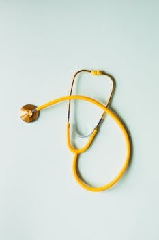 Top view of yellow medical stethoscope placed on white surface during coronavirus pandemic